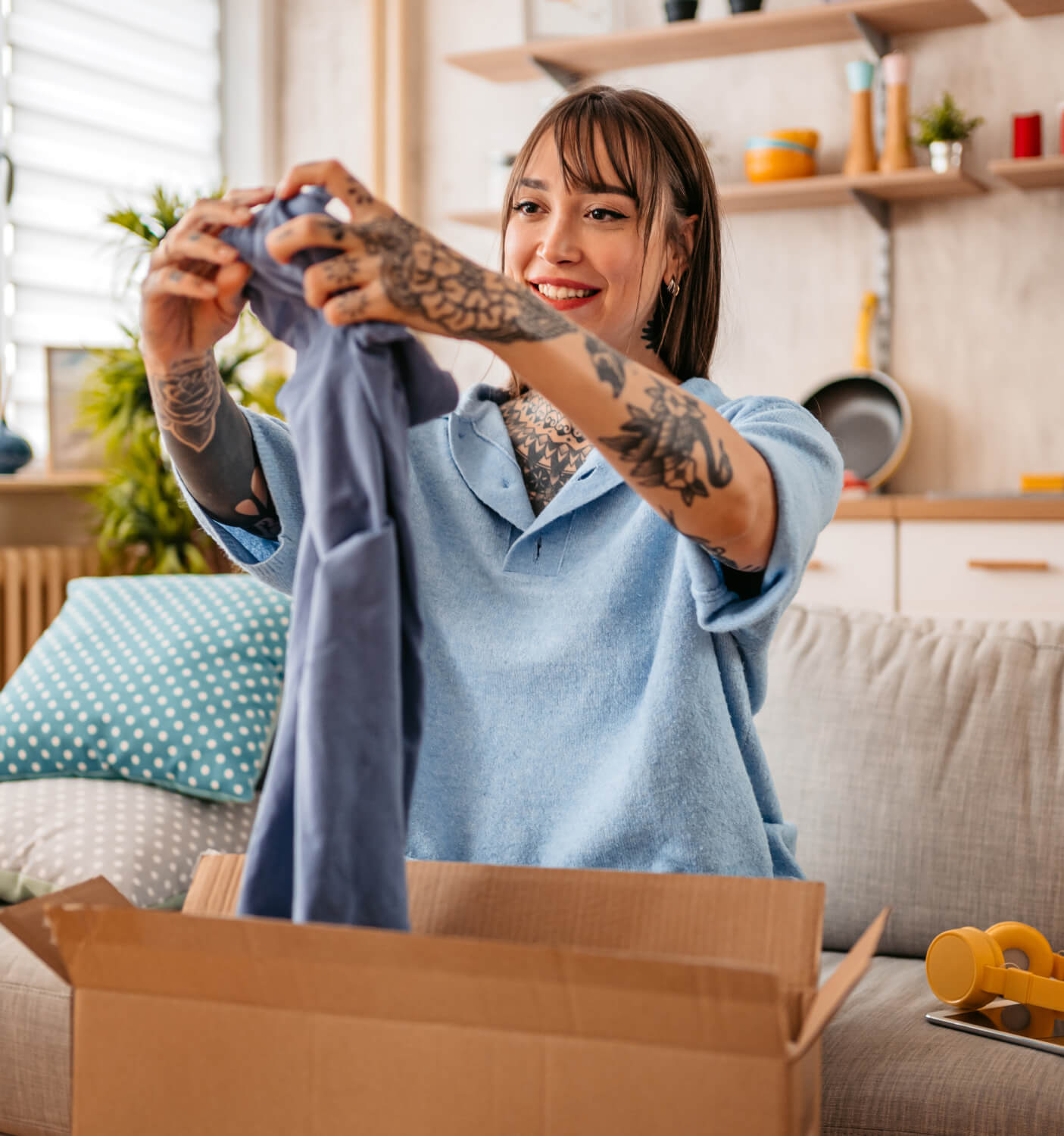 Girl sitting on a couch, opening up a clothing delivery